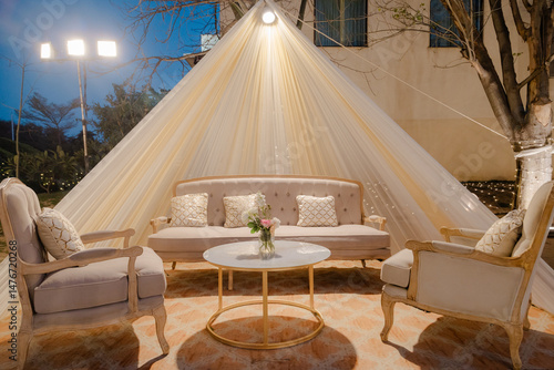 Outdoor Seating Area: A cozy outdoor lounge setup with a sofa, chairs, and a coffee table, all covered by a light fabric canopy for an inviting ambiance.