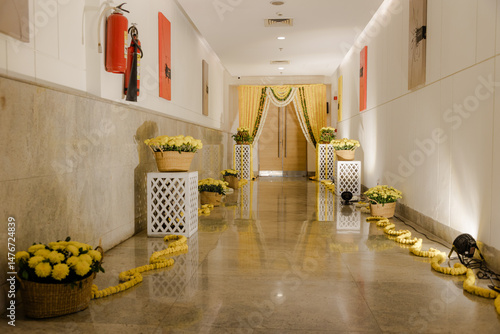 Hallway decorated with yellow flowers and garlands, leading to draped entrance, creating a festive and elegant atmosphere.