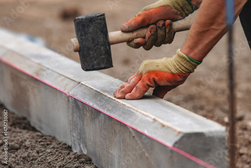 Schilderij op canvas Close-up of builder hands laying new chamfer kerb on semy-dry concrete mix durin