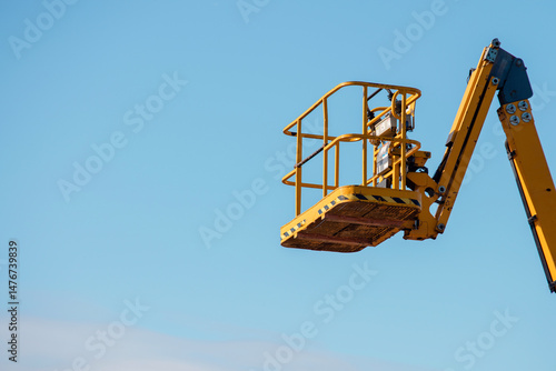 Wallpaper Mural Elevated boom lift platform cherry picker against clear blue sky during daytime works on construction site with bright sunlight illuminating the machinery Torontodigital.ca