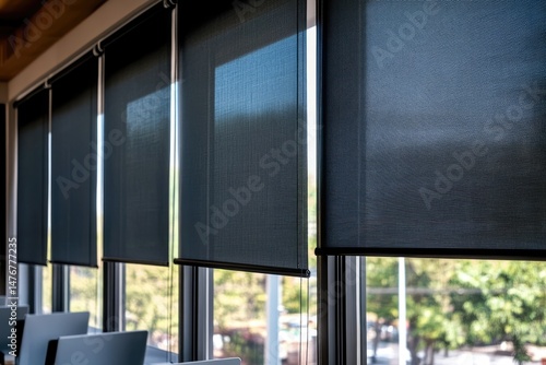 Dark gray window blinds covering a modern office space's large windows.  The blinds are rolled down, providing privacy and light control.  