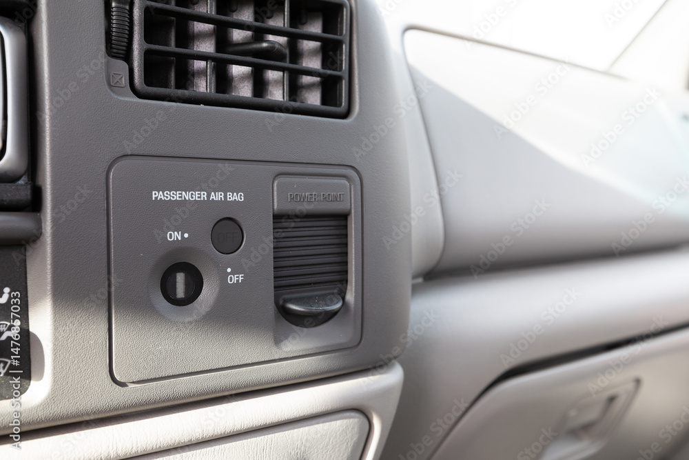 Obraz premium Close up of passenger airbag control switch and power outlet port on the dashboard of an early 2000s American pickup truck.