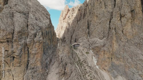 Wallpaper Mural Panning drone shot of the remote Toni Demetz Hut perched high in the Dolomites, with sweeping views of rugged cliffs, alpine trails, and dramatic mountain scenery Torontodigital.ca