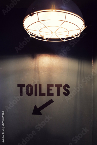arrow pointing downstairs to dimly lit restrooms in sketchy area of the building