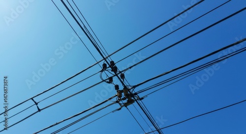 Power lines crisscrossing a clear blue sky