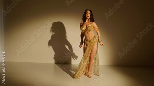A captivating belly dancer, shimmering in gold, her movements a mesmerizing spectacle. Golden light illuminates a dancer's graceful form, showcasing the artistry of belly dance.	