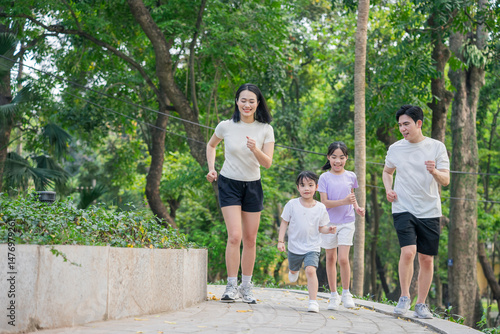 Family enjoying a morning jog through a lush park surrounded by green trees and nature