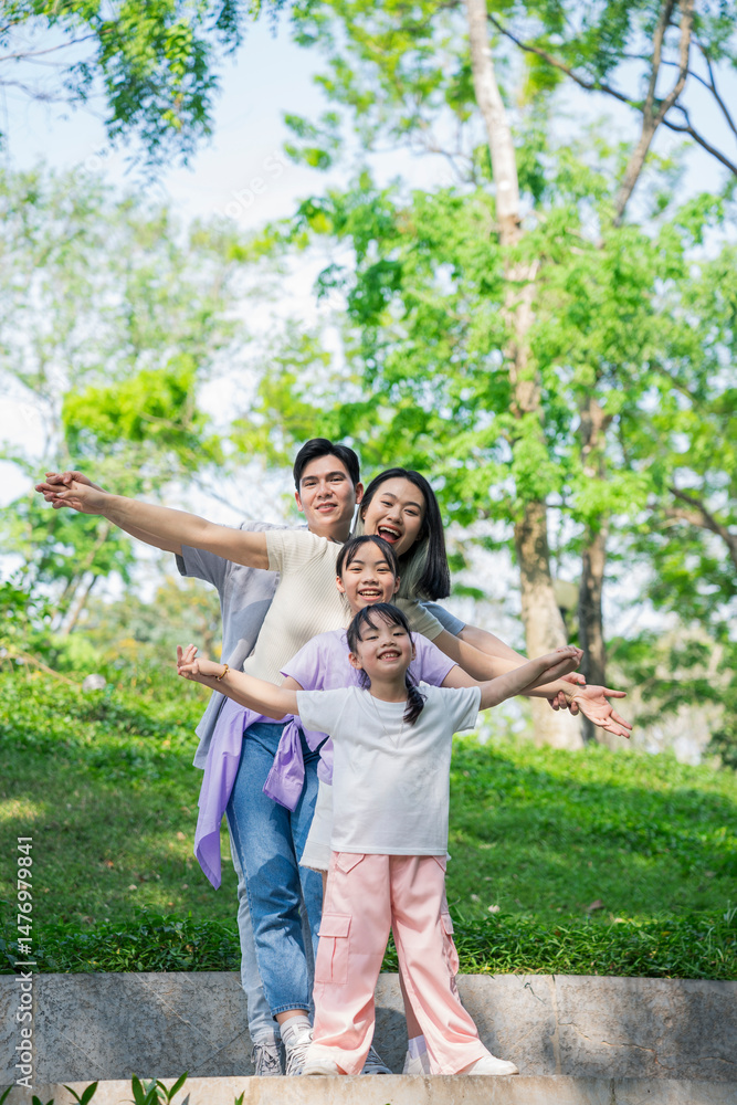 Fototapeta premium Family enjoying a joyful moment outdoors in a green park setting on a sunny day