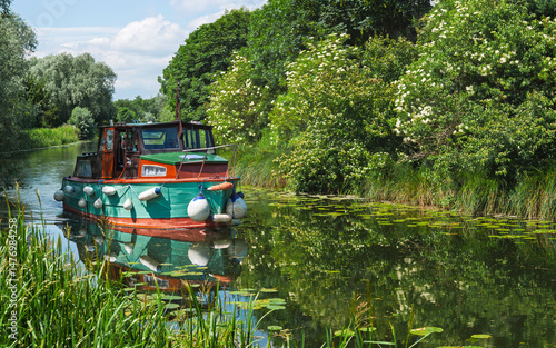 Small river-boat makes headway down the beck. Beverley, UK.