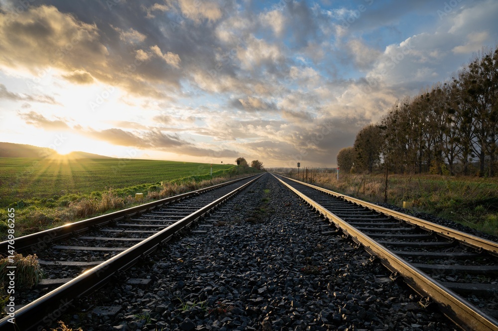 Obraz premium The sun is setting over a train track in the country