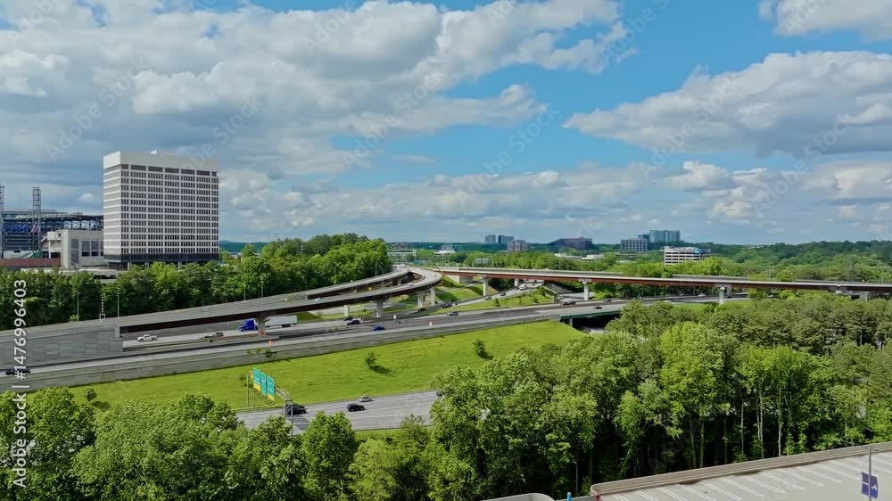 Traffic scene with trucks and cars in american suburb. Overpass highway with green trees and clouds at sky. Aerial wide shot. Office complex block in Atlanta, Georgia. Traffic scene with trucks and cars in american suburb. Overpass highway with green trees and clouds at sky. Aerial wide shot. Office complex block in Atlanta, Georgia.