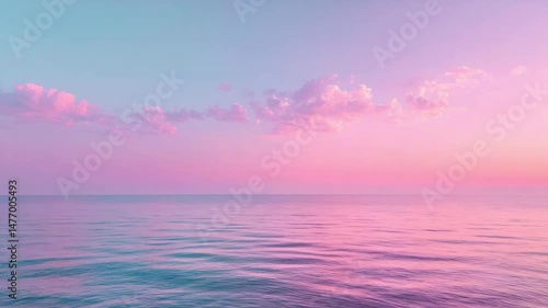 Calm ocean water under pastel pink and purple sky with soft clouds at sunset horizon