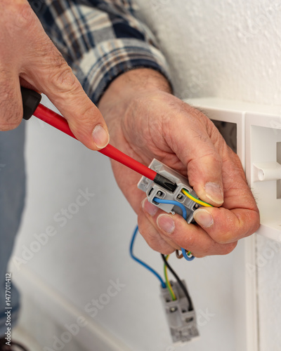 Wallpaper Mural Electrician worker with screwdriver fixes electrical wires in the terminals of the socket of an electrical system. Construction industry. Torontodigital.ca