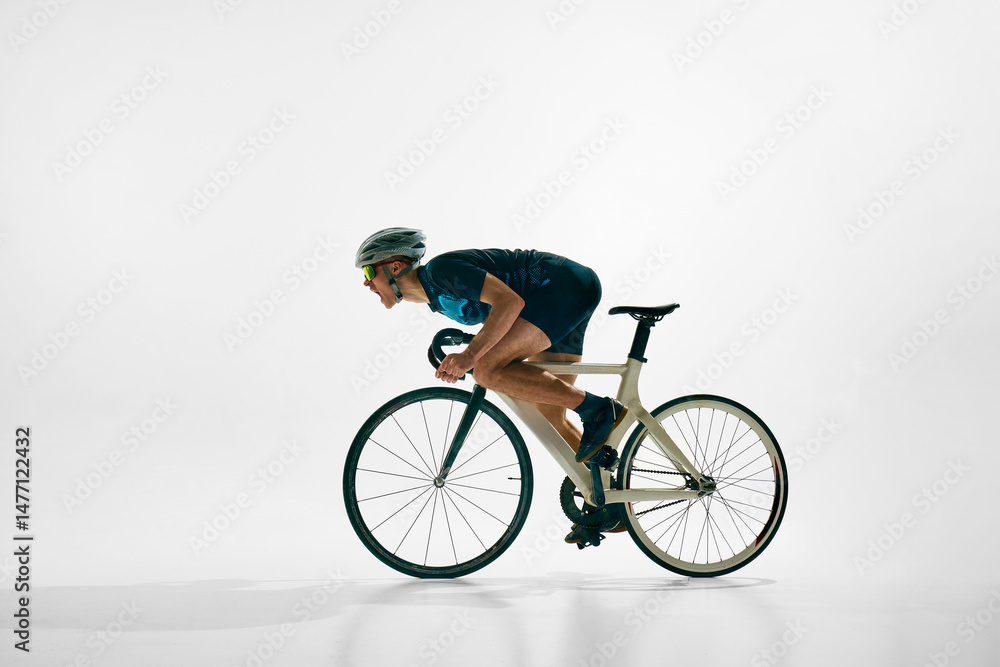 Obraz premium Side view image of young concentrated man, professional cyclist in motion on bicycle, riding isolated on white background. Concept of sport, competition, active lifestyle, endurance
