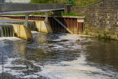 Fotografi Industrial foamy water discharge into River Aire at a weir near Leeds, West Yorkshire, UK