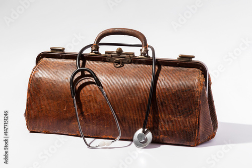 Vintage doctor bag and stethoscope resting on white background