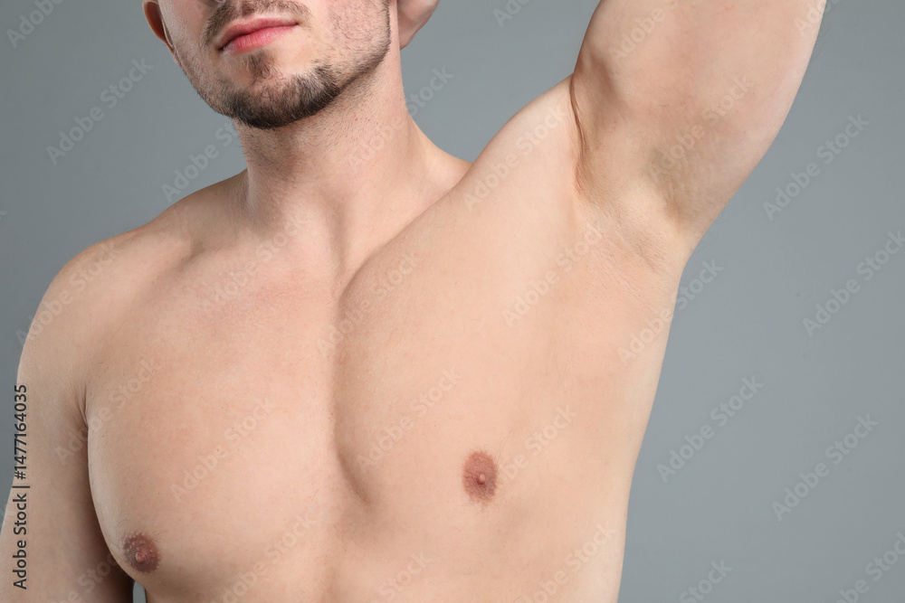 Fototapeta premium Young man showing smooth armpit after epilation procedure on light grey background, closeup