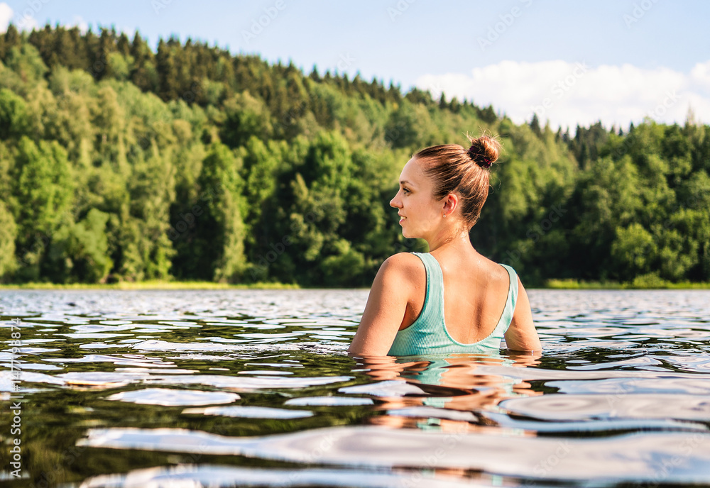 Fototapeta premium Lake swimming in nature. Woman in Finland in summer. Forest and river water. Finnish bathing. Happy morning. People wellness in Scandinavia.