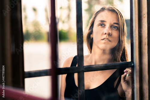 Fotografía Woman peeking through window inside a house