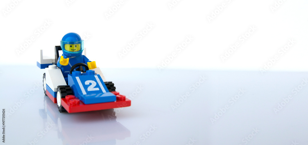 Obraz premium Coche de carreras azul y piloto al volante de LEGO oficial. Imagen aislada 
