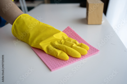 Foto female hand in yellow gloves cleaning white table at house