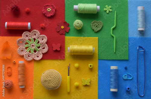 Flat lay arrangement of crochet element, green and red yarn, needles, clips, felt background in complementary colors, tools and thread for colorful handmade textile DIY craft or decorative composition