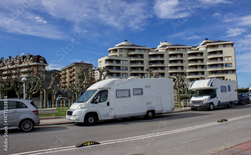 mobile homes stand by the road next to modern houses