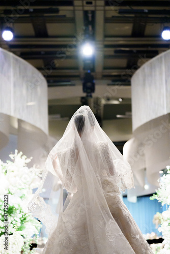 Bride in Veil Standing Under Wedding Lights Indoors
