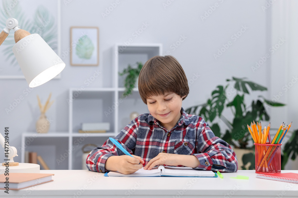 Cute little boy doing homework at table indoors Cute little boy doing homework at table indoors