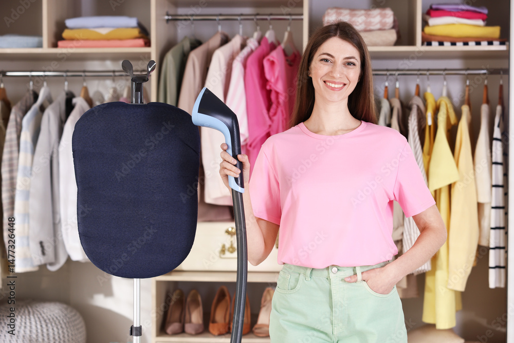 Obraz premium Smiling woman with stand steamer at home