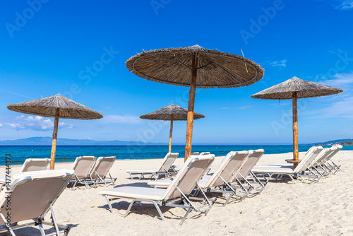 Sonnenliegen und Strohdächer am Strand von Kassandra