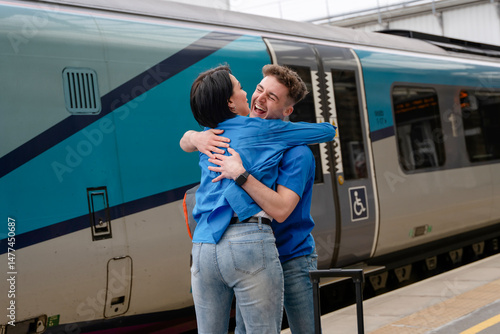 People reunite joyfully at the train station embracing after a long journey on a sunny day