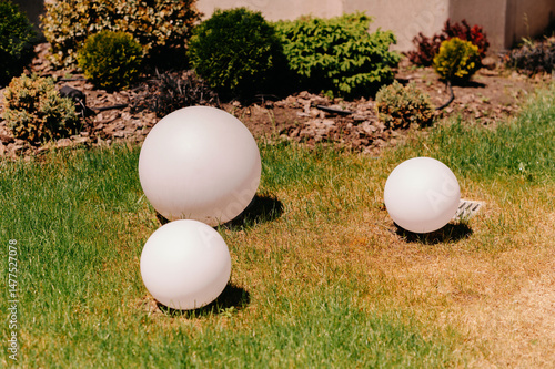 Stylish round spherical lights in various sizes beautifully enhance outdoor aesthetics on a sunny summer day