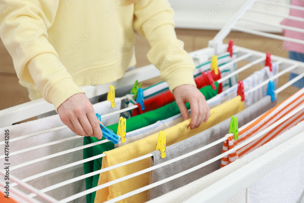 Naklejka premium Woman hanging fresh clean laundry on drying rack at home, closeup