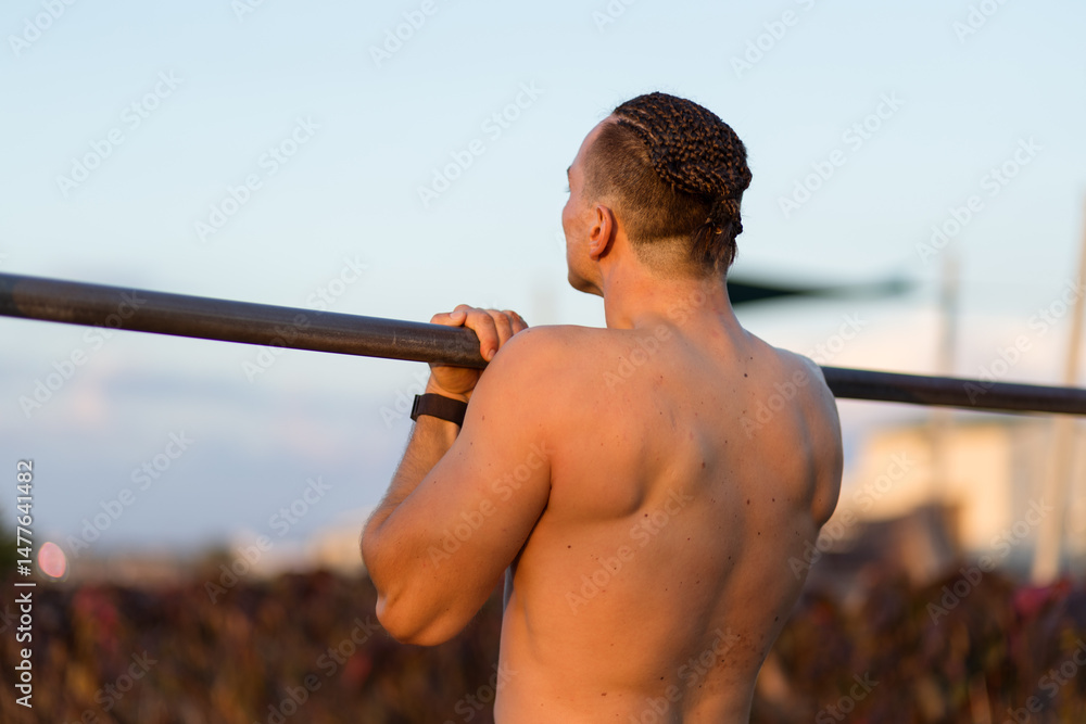 Fotografie Young man's back as he performs a chin up