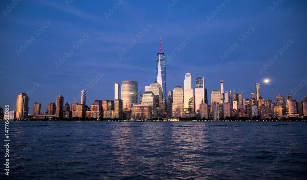 Obraz premium new york city skyline view during blue hour just after sunset (dusk nightfall night time photography from jersey city waterfront) hudson river downtown skyscrapers tall commercial buildings reflecting