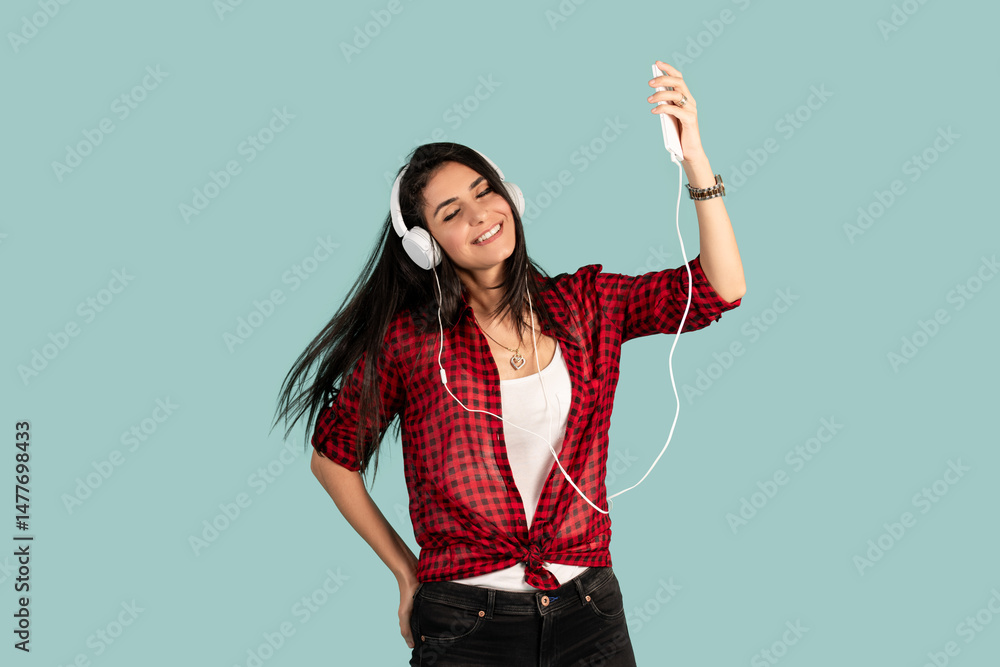 Cheerful young brunette woman girl in striped t- shirt posing isolated on pastel blue background. People lifestyle concept. Listen music with headphones and dancing. Cheerful young brunette woman girl in striped t- shirt posing isolated on pastel blue background. People lifestyle concept. Listen music with headphones and dancing.