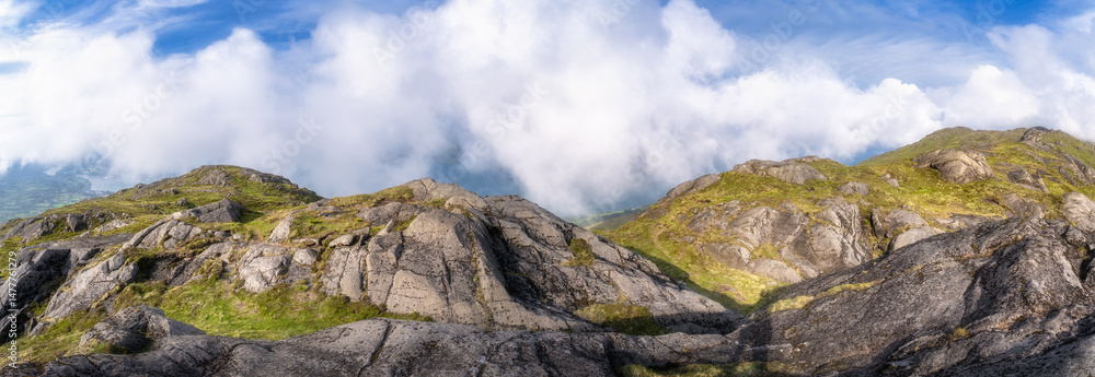 Obraz premium Behold the stunning panoramic view of rugged Slieve Foye mountains beautifully adorned with vibrant greenery, all set under a clear blue sky that is filled with fluffy clouds, Carlingford, Ireland
