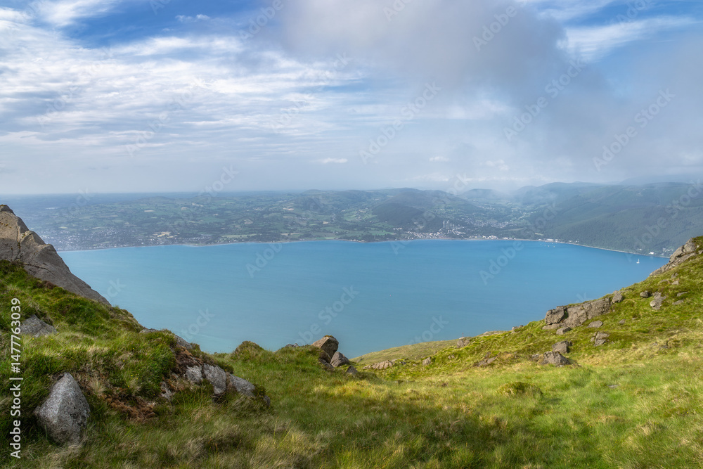 Obraz premium This breathtaking view showcases a serene bay surrounded by lush hills and a cloudy sky, perfect for nature lovers and outdoor enthusiasts seeking adventure, Carlingford, Ireland