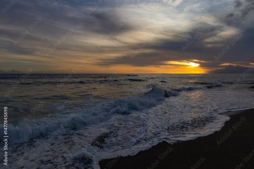 Obraz premium Breathtaking sunset at Bali. Bright sunrise sky against wavy ocean and palm trees, Bali, Indinesia
