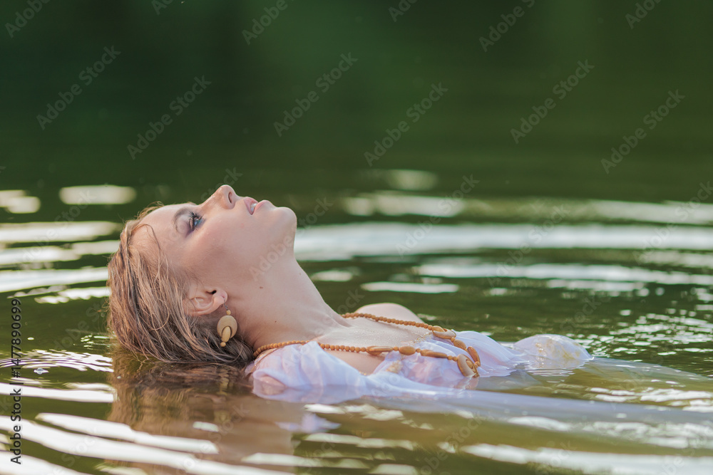 Fototapeta premium Beautiful Girl with long hair swims and dances in water