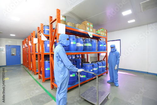 Pharmaceutical warehouse with blue storage containers on racks, clean epoxy flooring, cleanroom environment in supplement or medicine manufacturing facility.