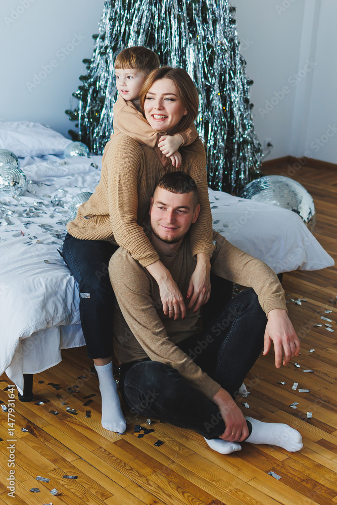 A joyful family portrait captured beautifully by the Christmas tree, showcasing cozy sweaters worn by all family members, which reflects warmth, love, and happiness during this festive season