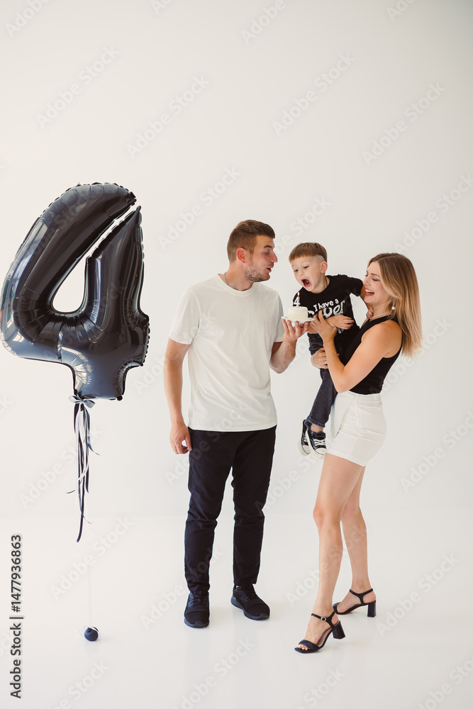 Happy young family dad, mom and boy around birthday cake. Celebrating children's birthday in family circle.