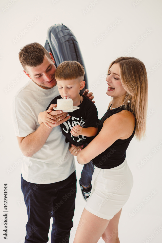 Happy young family dad, mom and boy around birthday cake. Celebrating children's birthday in family circle.