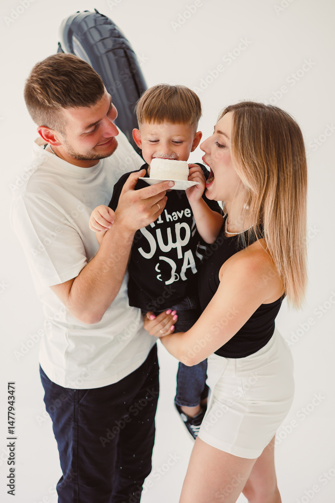 Happy young family dad, mom and boy around birthday cake. Celebrating children's birthday in family circle.