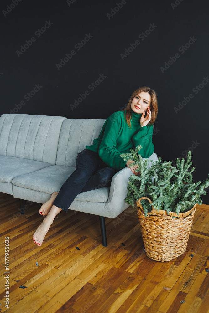 In this casual home living scene, a stylish woman enjoys moments of relaxation on a modern sofa adorned with beautiful indoor plants that add a touch of greenery and elegance to her home