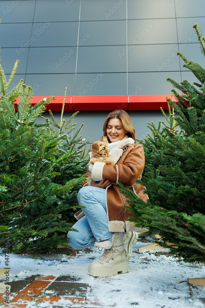 Charming Winter Moment A Young Woman Holding a Cute Dog, Surrounded by Beautiful Christmas Trees, Creating a Wonderful Atmosphere Full of Joy and Celebration in the Festive Season