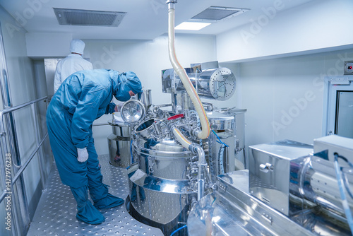 pharmaceutical worker using large machine. person checking medicine liquid making vessel. medicine making factory. person wearing a ppe kit in a factory. healthcare concept. Pharmaceutical industry	