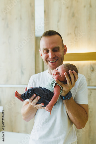 Obraz na płótnie A Joyful Father Holding His Newborn Baby in a Beautiful, Modern Nursery Setting, Encapsulating the Essence of Bonding and Care Between Parent and Child in a Cozy, Loving Environment w salonie